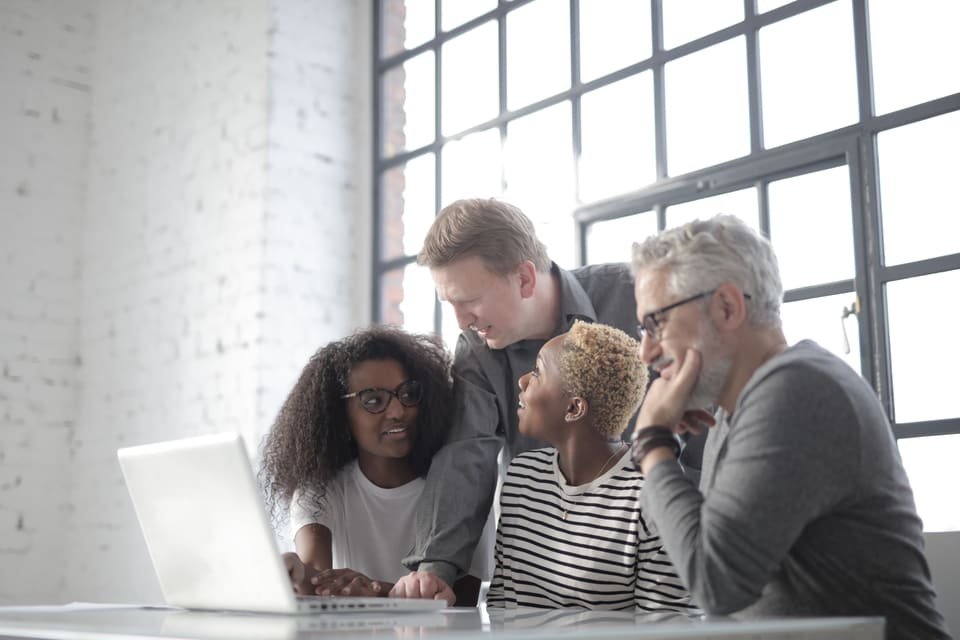 Colleagues working together around a laptop in a bright office.