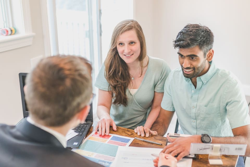 A smiling couple reviewing information with a real estate professional.